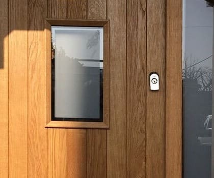 Close detail of an oak front door with a glazed panel and arched frame