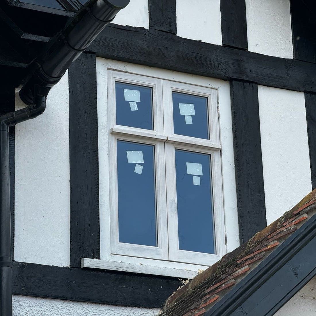 Painted timber casement window in a black and white timber-framed wall